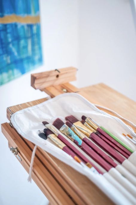 Pinsel in Stoffrolle auf einer Holzstaffelei – Kunst & Gespräche, Malmaterialien im Atelier